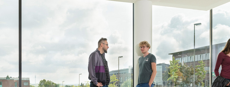 Four people are talking to each other in front of a window.
