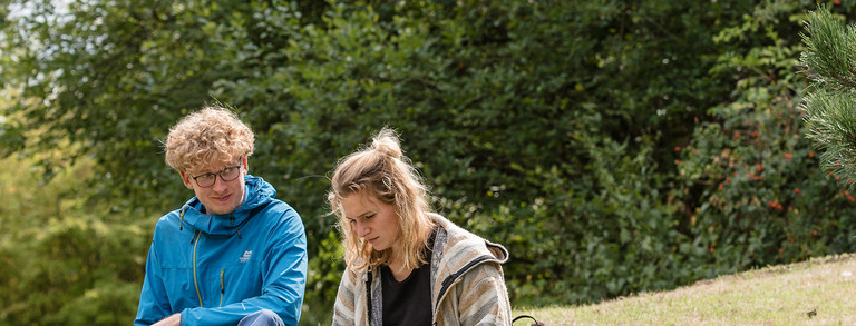 Two students are sitting on the green grass